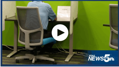 Screenshot of a video from KOAA of the back of a job seeker on the phone at the Pikes Peak Workforce Center